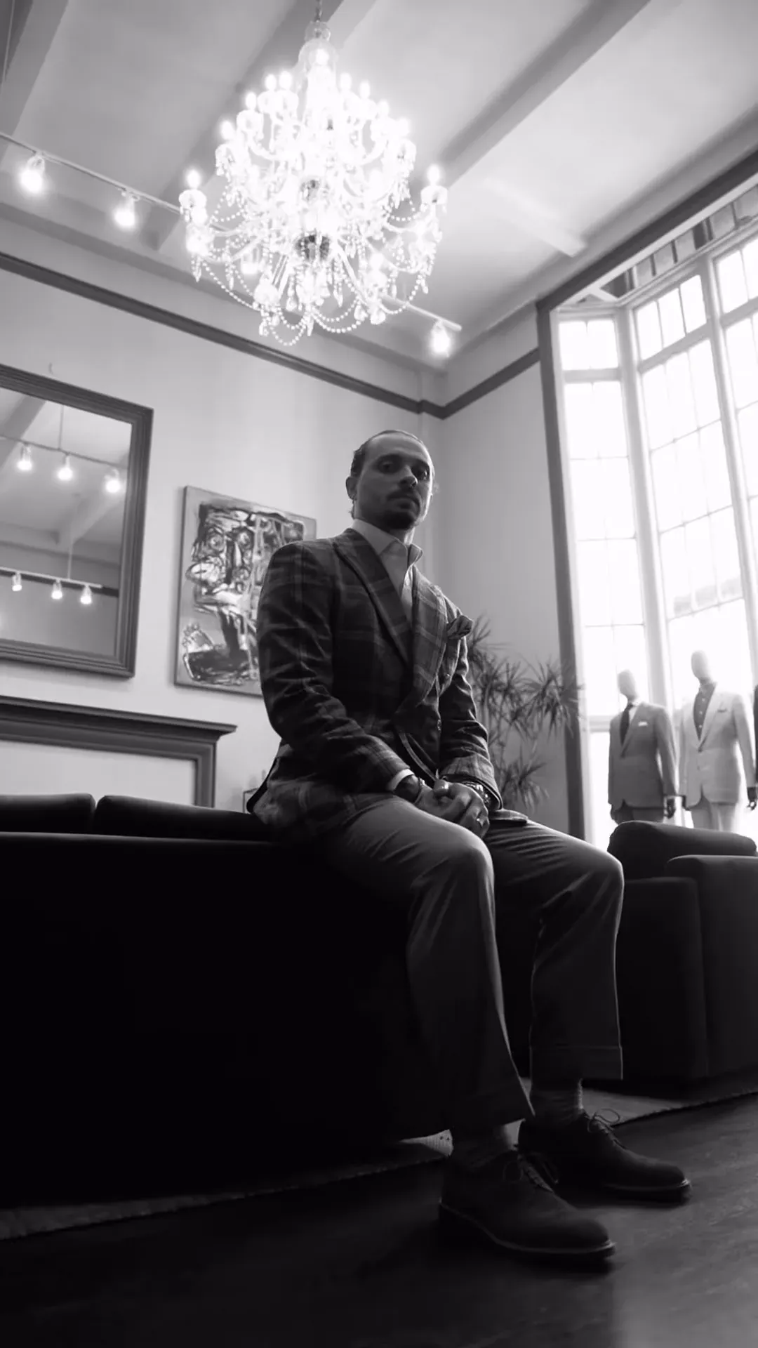 Nick Matic in a tailored suit, seated under a chandelier